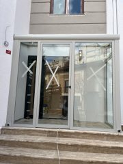 Villa girişinde cam rüzgarlık sistemi antrasit alüminyum sürgülü cam giriş tasarımı